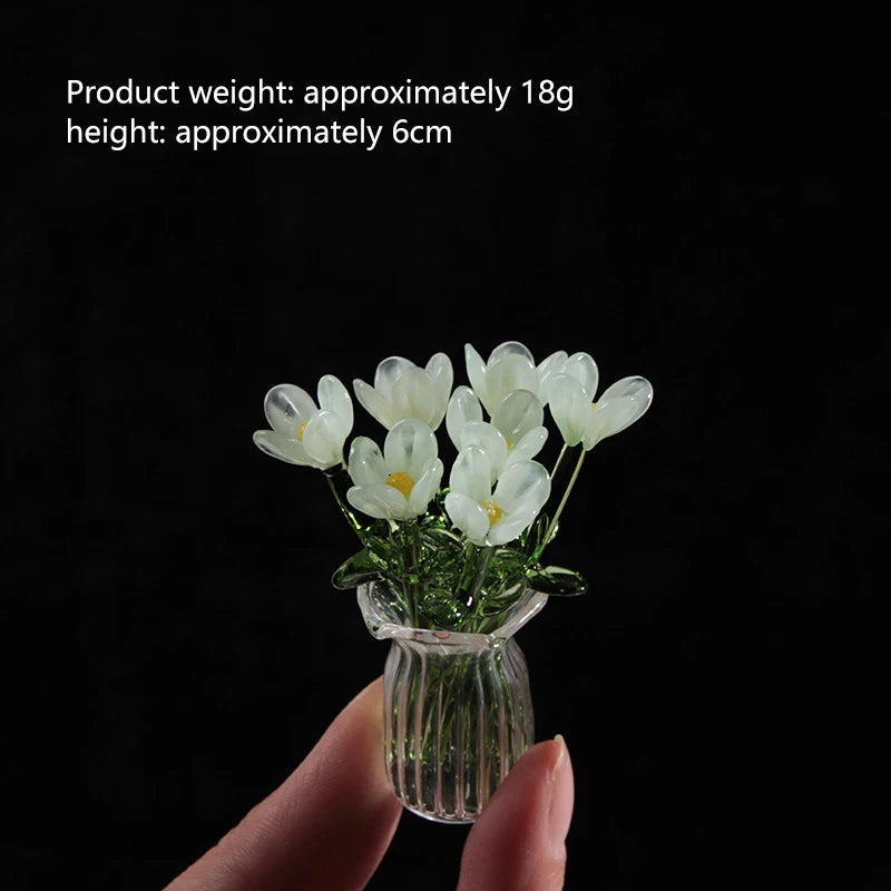 A hand holds a small glass vase filled with white tulips for home decor.