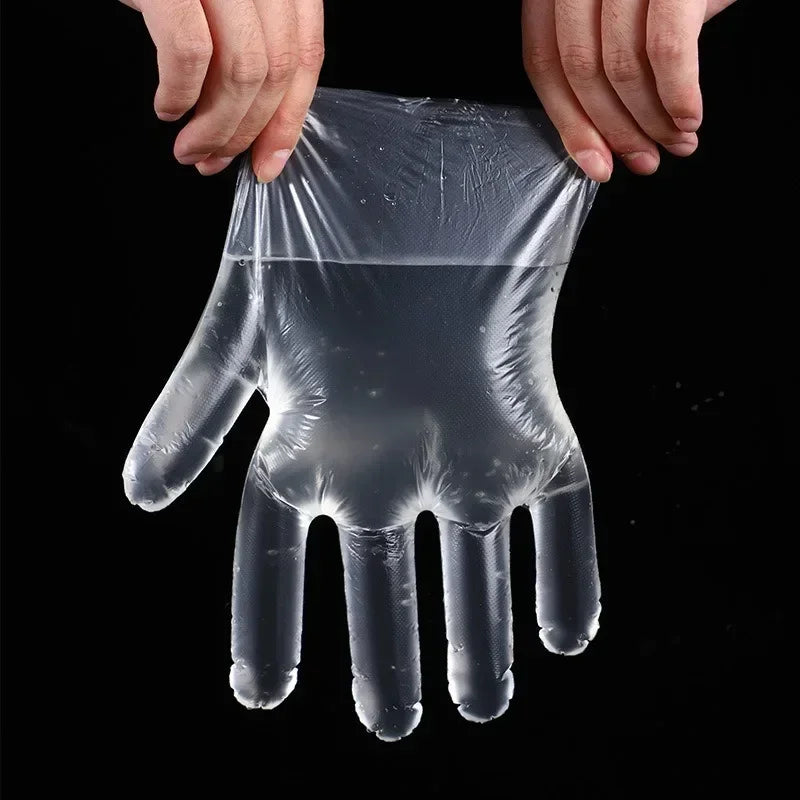 A hand is holding a clear disposable plastic glove for kitchen and food preparation.