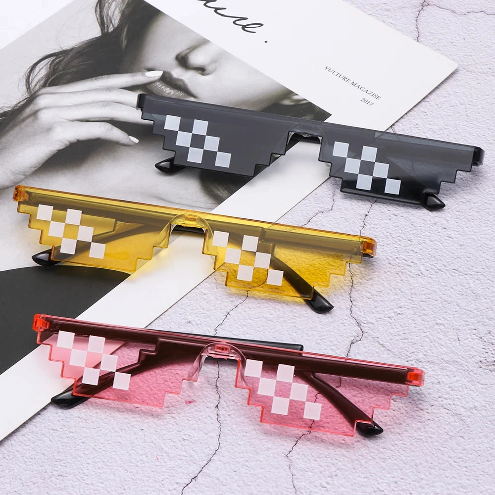 A display of three pairs of pixel mosaic sunglasses in black, yellow, and pink shades on a white textured surface.