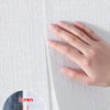 Une main applique un autocollant mural blanc et texturé sur une surface, illustrant la finesse du produit.