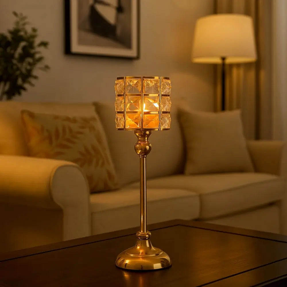 Un portavelas de cristal dorado con un brillo cálido se asienta sobre una mesa de madera oscura.