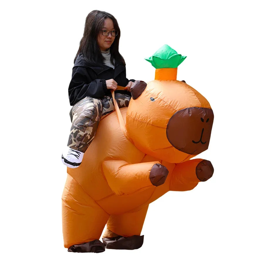An adult woman is posing with an orange inflatable capybara costume that resembles a ride-on suit.