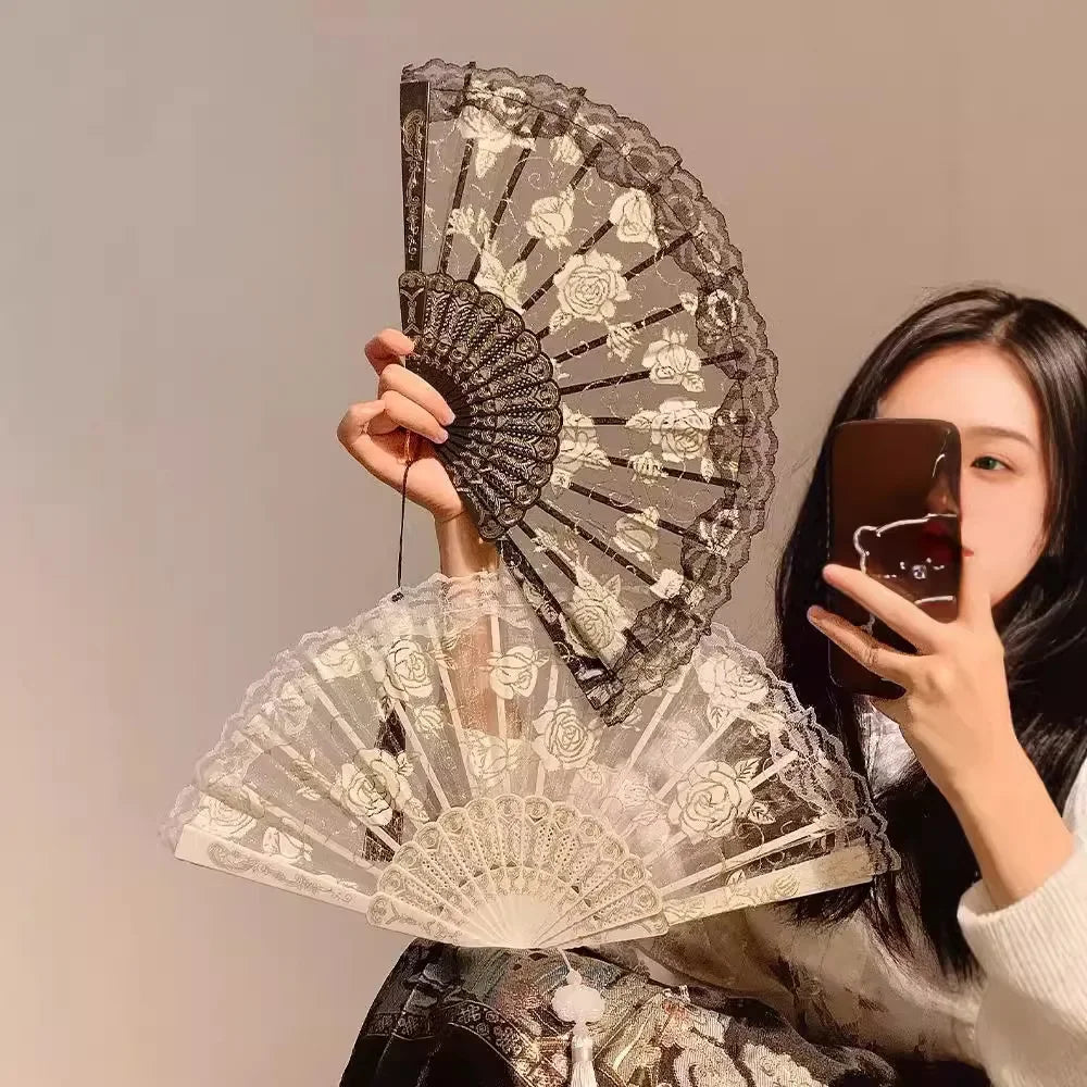 A woman holds an elegant lace rose folding fan with intricate floral patterns against a light background.