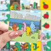 A hand holds a sticker card featuring cartoon dinosaurs and a cityscape background.