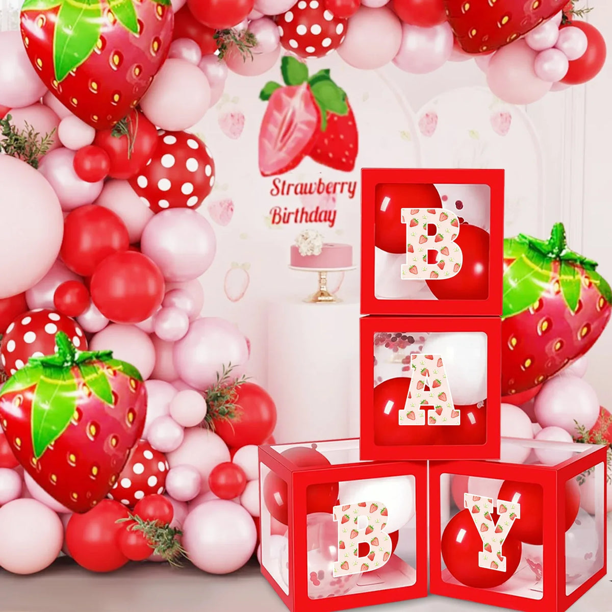 A set of strawberry theme birthday decorations featuring red and pink spherical ornaments and a banner.