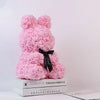 Rosa künstlicher Rosen-Teddybär mit schwarzer Schleife auf einem Stapel Bücher