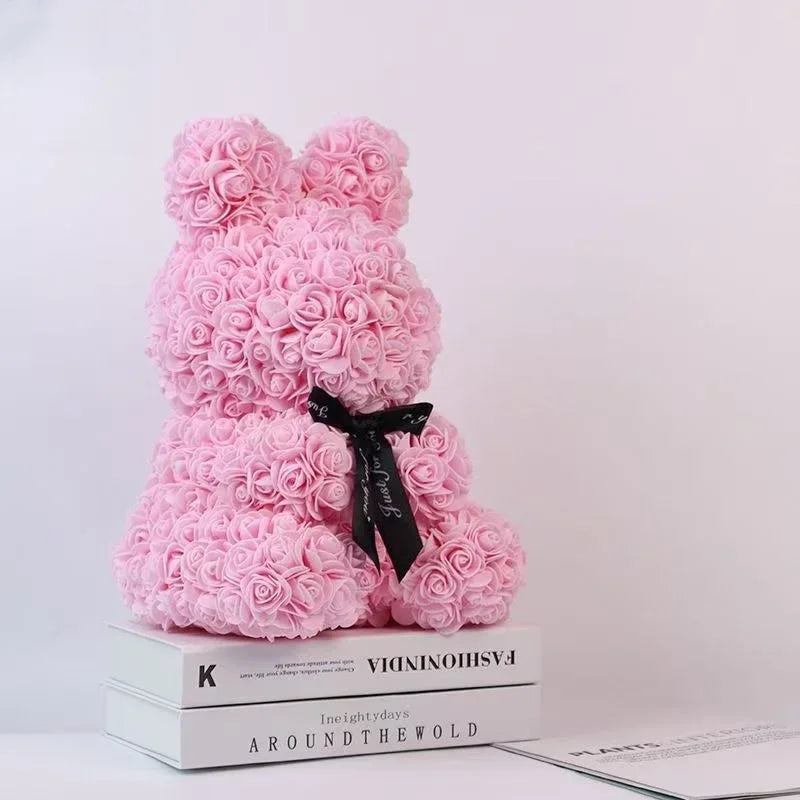 Rosa künstlicher Rosen-Teddybär mit schwarzer Schleife auf einem Stapel Bücher