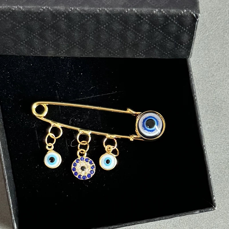 Elegant gold and silver evil eye brooch pin featuring blue and white glass eyes.