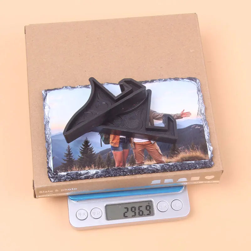 A rectangular slate photo frame featuring a black silhouette of a person against a natural landscape, displayed in a cardboar