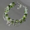 A bracelet made of clear glass beads and green natural stone flowers resembling a lily of the valley.