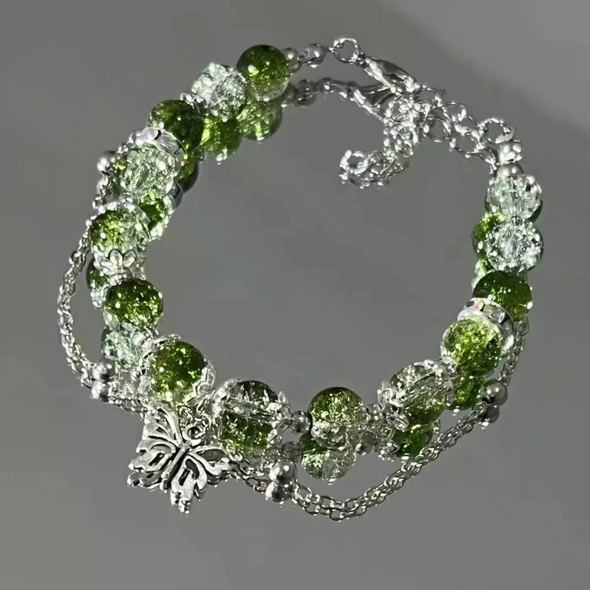 A bracelet made of clear glass beads and green natural stone flowers resembling a lily of the valley.