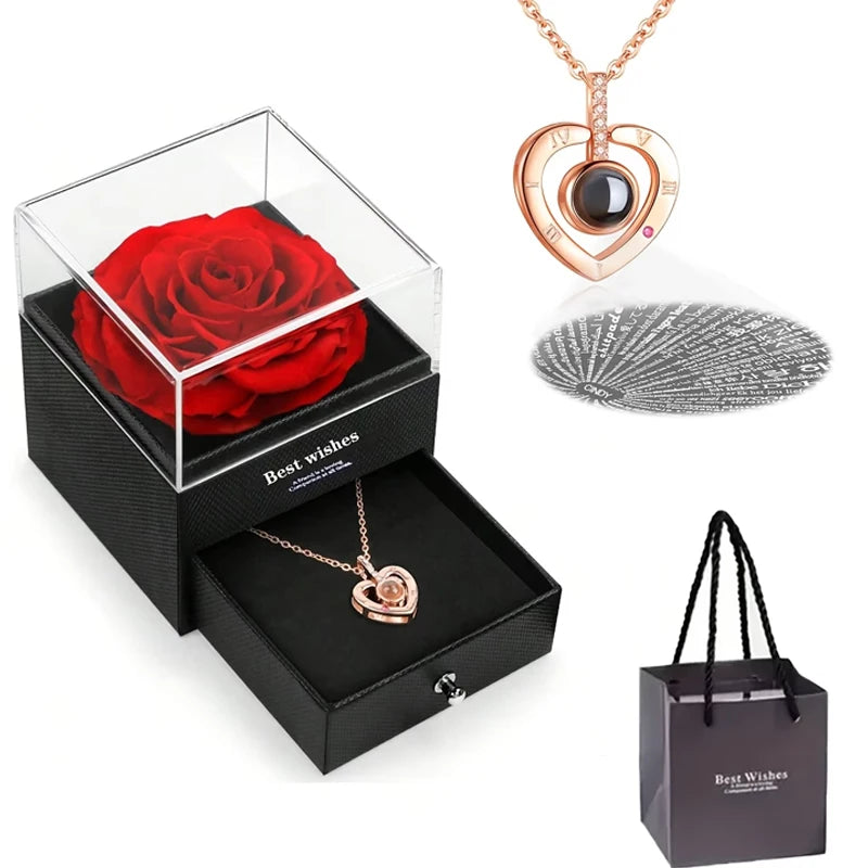 Un coffret noir avec une rose rouge conservée, un collier cœur or et un charm en ton argent.