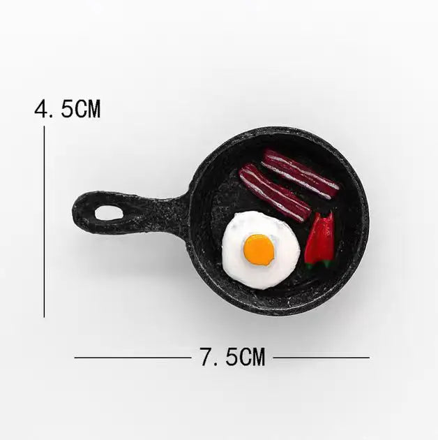 A black silicone mold containing three red fruit shapes, including a sliced banana and avocado, used for making fridge magnet
