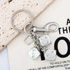 A silver keychain featuring a golden dice charm and a lucky charm design.