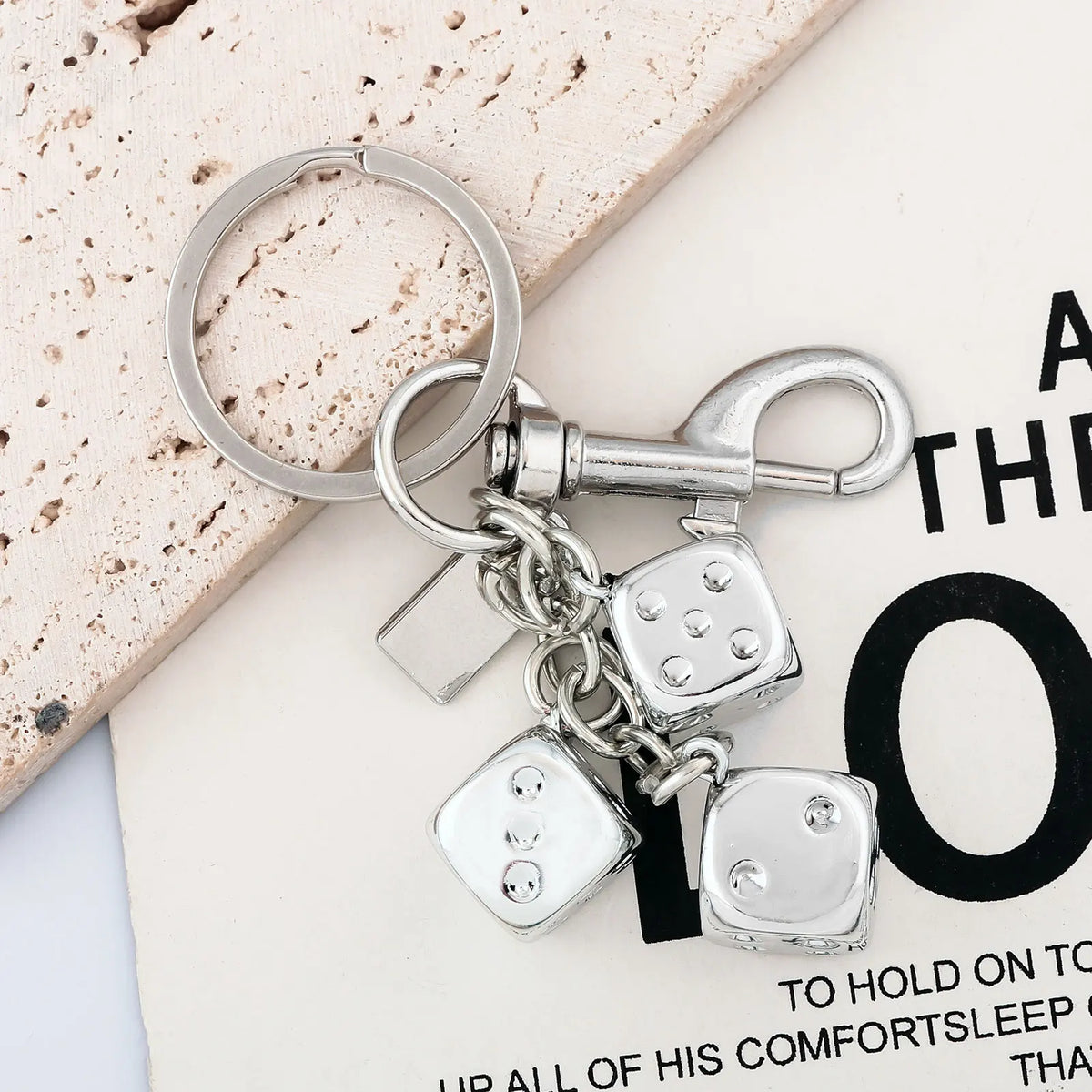 A silver keychain featuring a golden dice charm and a lucky charm design.