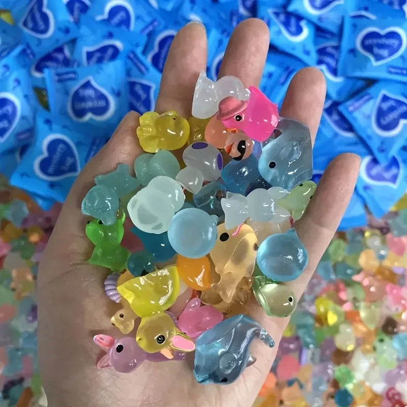 A hand holds a collection of glow in the dark resin decor pieces, including various colored and shaped items.