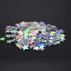 Un tas de confettis en acrylique laser or et argent éparpillés sur une surface sombre.