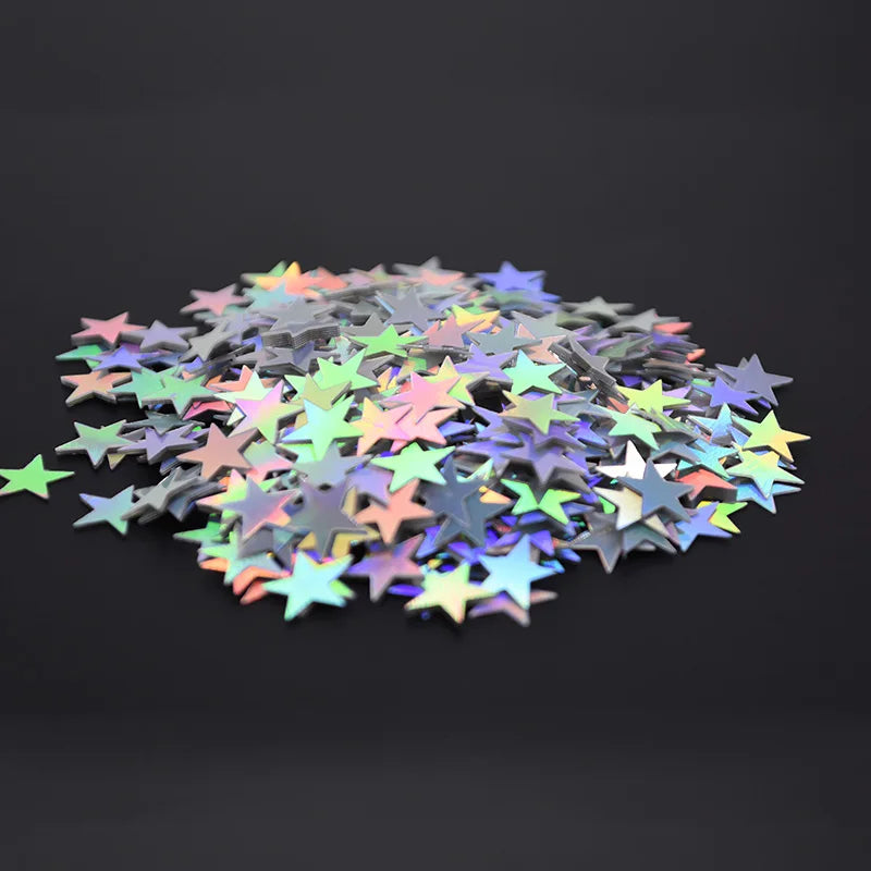 Un tas de confettis en acrylique laser or et argent éparpillés sur une surface sombre.