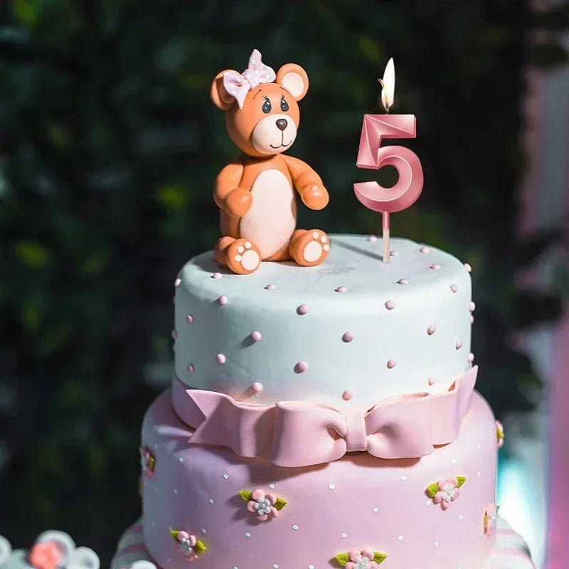 A two-tiered birthday cake decorated with pink and mint green frosting, featuring a teddy bear topper and a large pink number