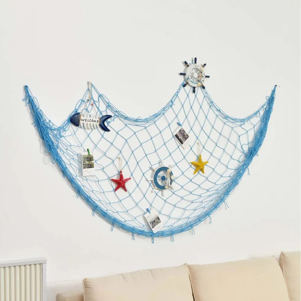 Red de pesca decorativa azul adornada con varias piezas, incluyendo una estrella de mar y un reloj.