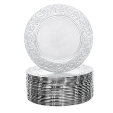 A stack of silver embossed charger plates with decorative rims.