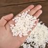 A hand holds a pile of white natural soy wax flakes for DIY candle making.