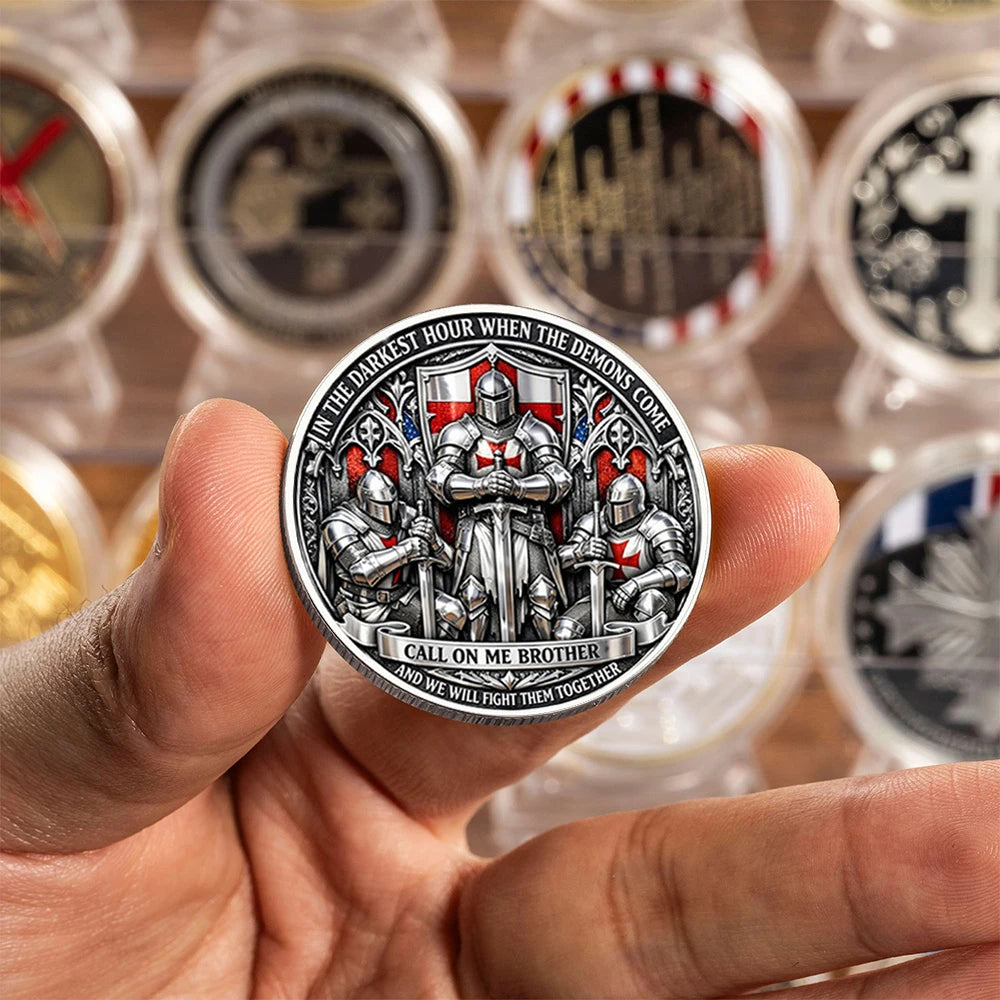A hand holds a silver-plated commemorative coin featuring a knight and a brother motif.