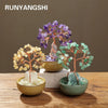 A natural crystal money tree with a rose quartz base displayed on a wooden surface.