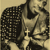 A close-up portrait of a man wearing a patterned shirt and necklace.