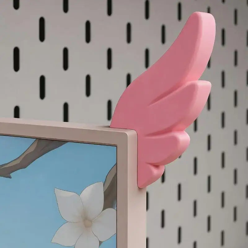 A pink 3D printed LED monitor wing decoration is displayed next to a framed picture featuring a white flower.