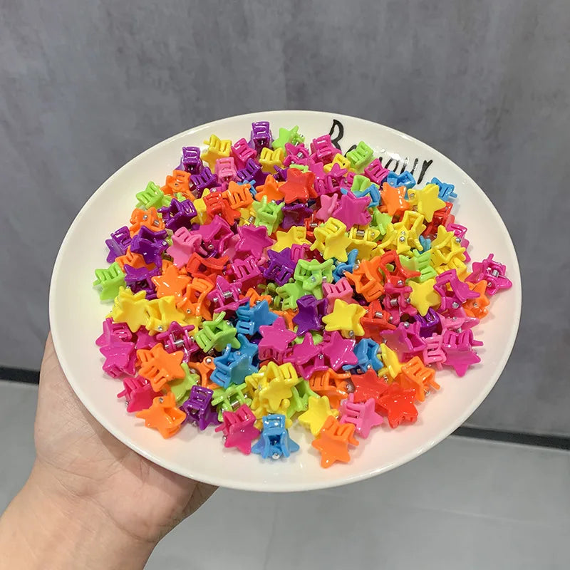 A pile of colorful flower and star hair claw clips for kids in various bright colors.