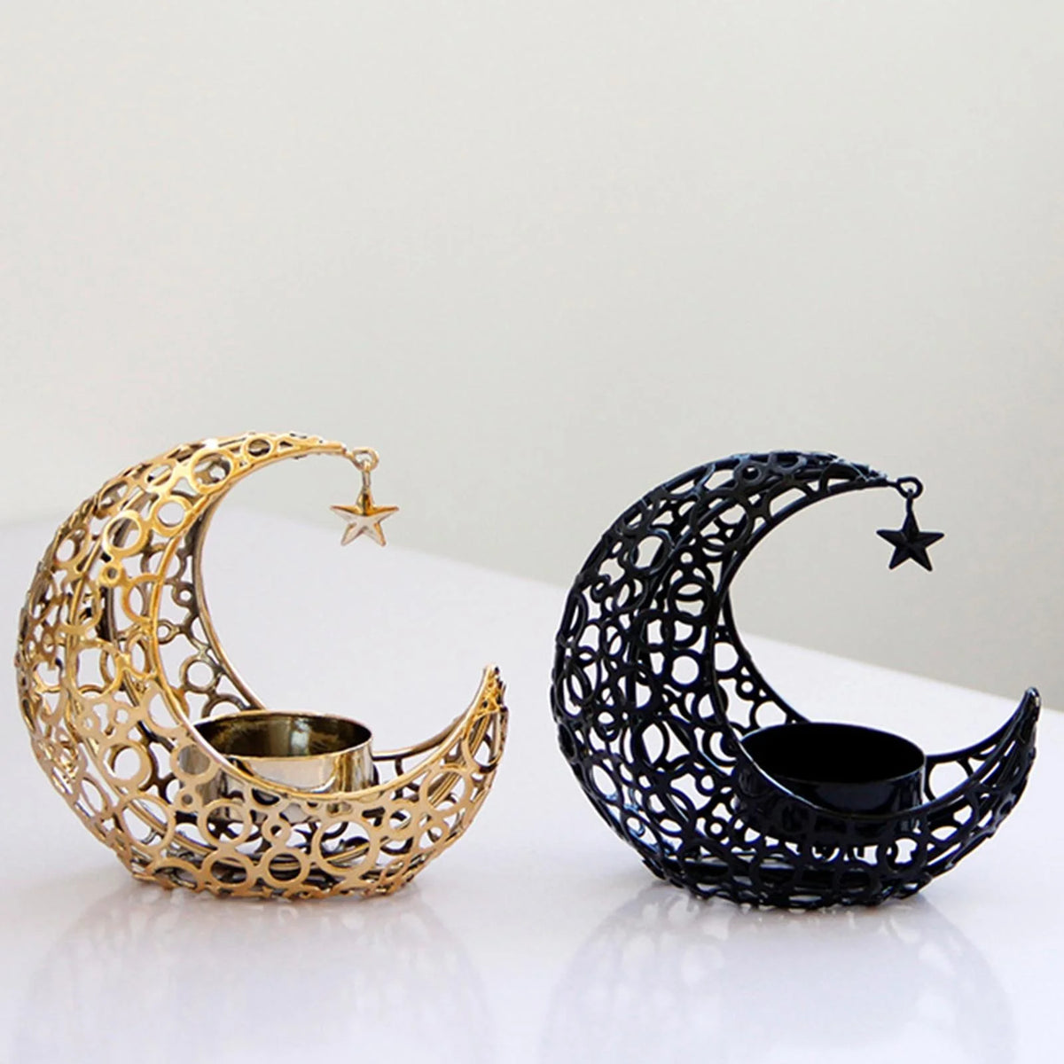 A pair of crescent moon candle holders, one gold and one black, featuring star accents.