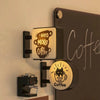 Magnetic fridge decor featuring a glowing sign that says I Need More Coffee and Wake Cup Coffee