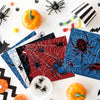 A collection of Halloween themed paper napkins featuring spiders and skeletons on a white surface.