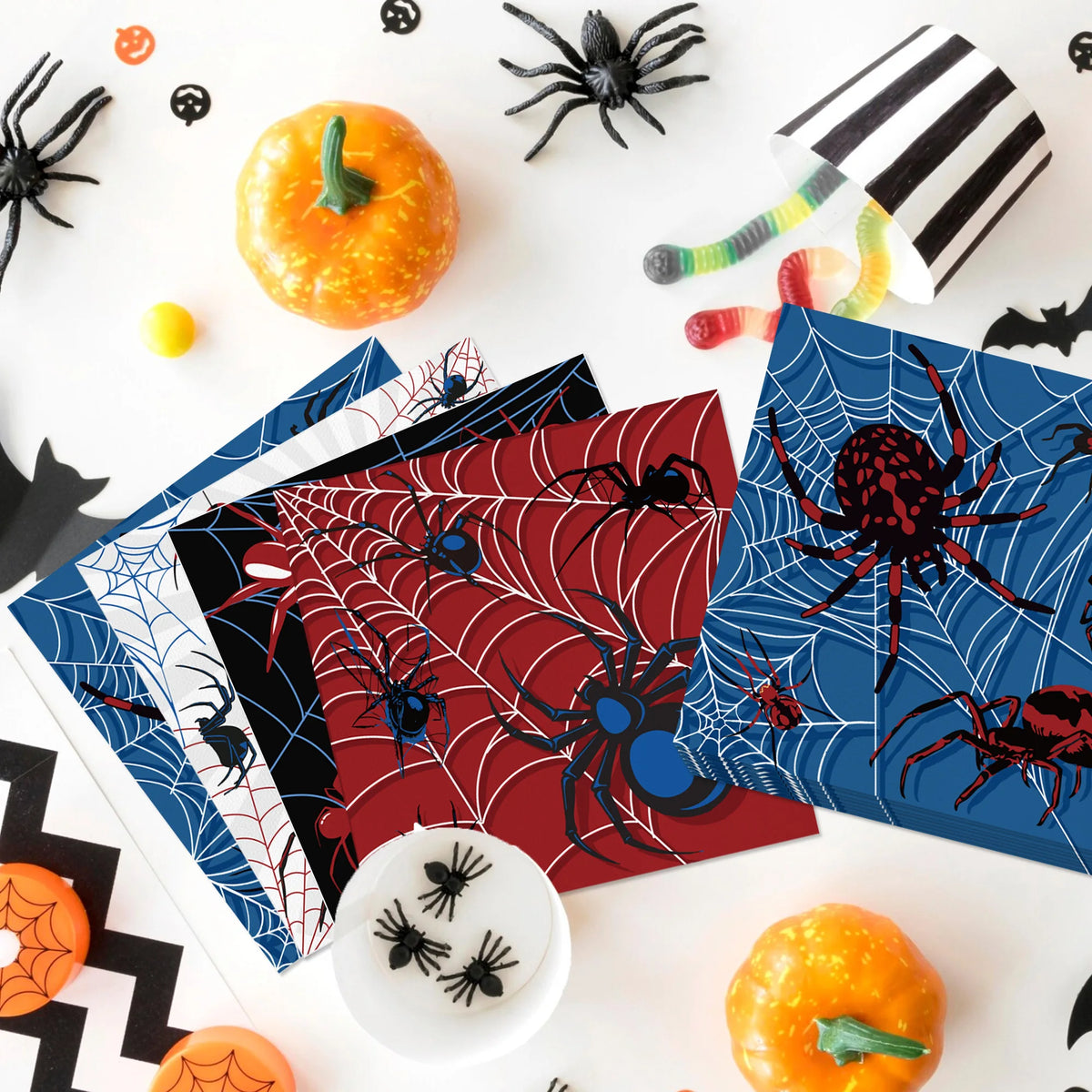 A collection of Halloween themed paper napkins featuring spiders and skeletons on a white surface.