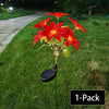A single solar-powered poinsettia garden light with red flowers illuminates a grassy lawn.