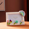 A white photo frame decorated with colorful foam blocks shaped like flowers and leaves, featuring the text Pin Living.