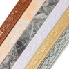 A close-up view of various 3D self-adhesive wall trim borders in gold, bronze, silver, and white finishes.