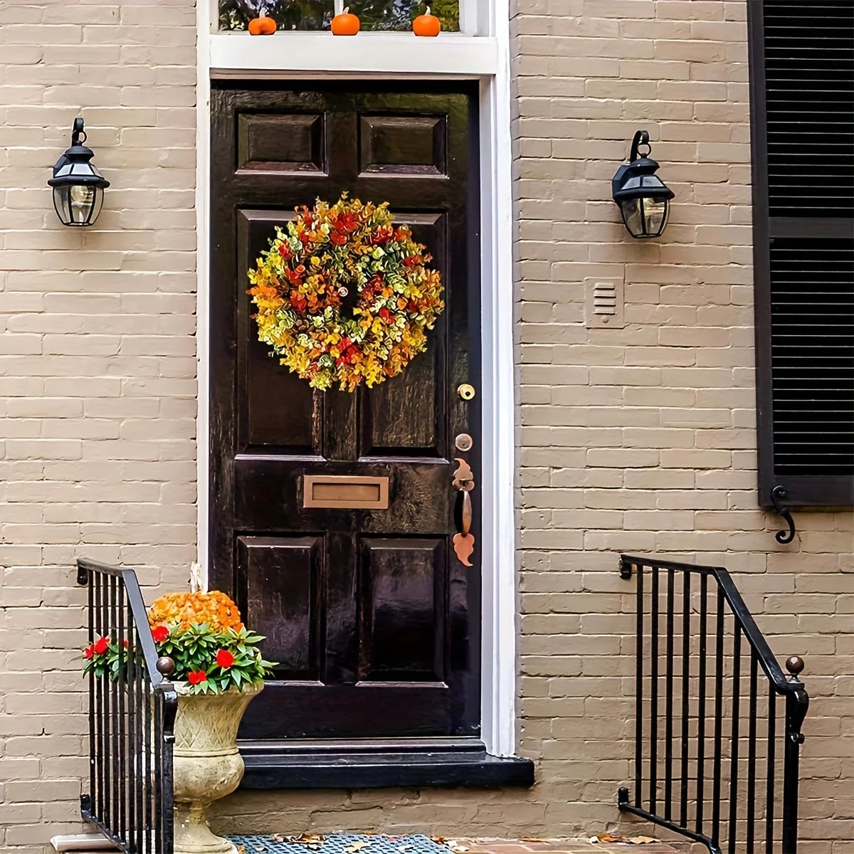 A black wooden door decorated with a large, colorful artificial flower wreath on a brick facade.