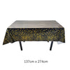 A rectangular table covered with a black cloth featuring gold polka dots, ready for use at an event.