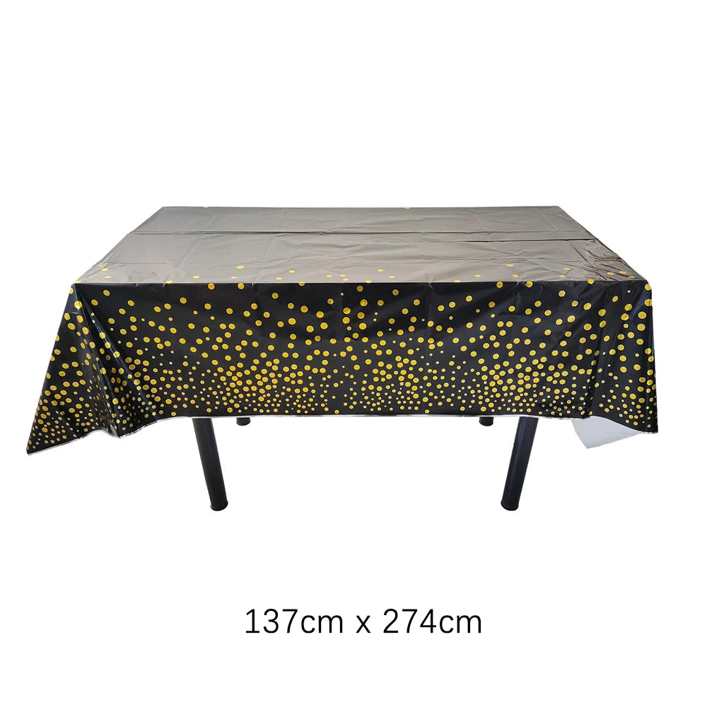 A rectangular table covered with a black cloth featuring gold polka dots, ready for use at an event.