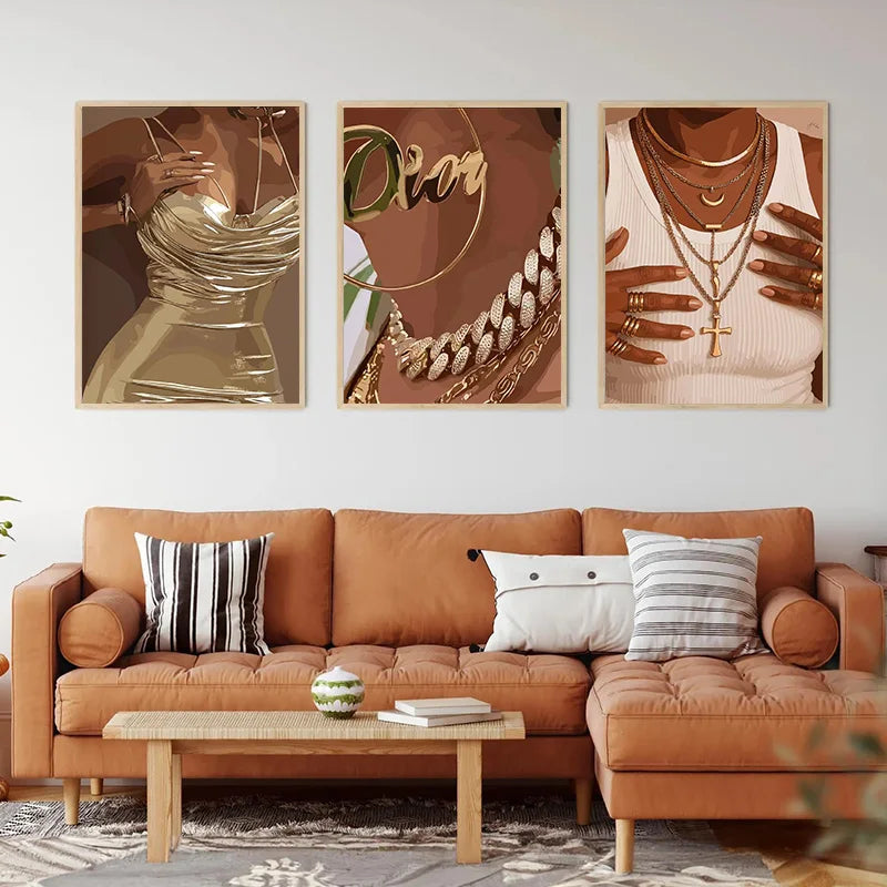 Ein Set aus drei Leinwanddrucken mit eleganten Gold- und Bronz-Nagelkunst-Designs, präsentiert über einem braunen Ledersofa.