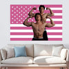 Un homme musclé pose devant un fond de drapeau américain rayé rose et blanc.