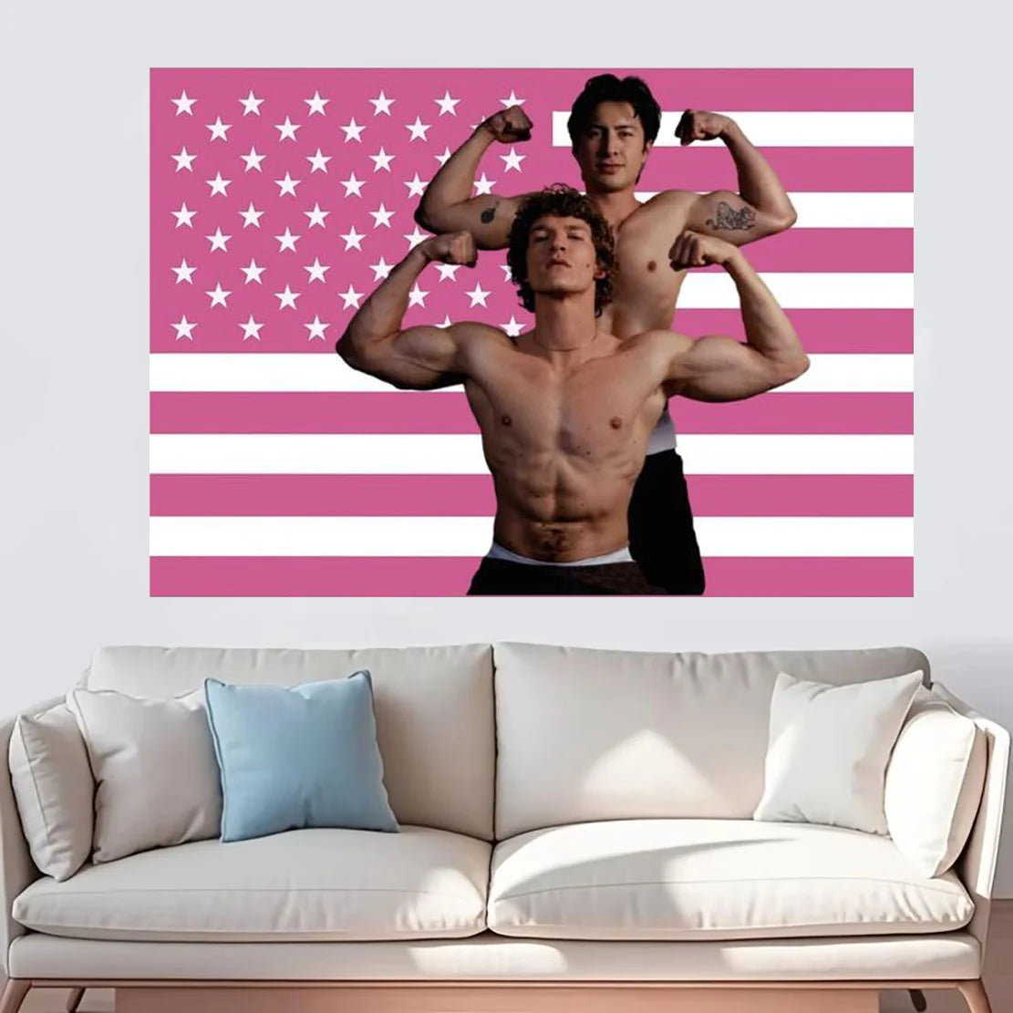 Un homme musclé pose devant un fond de drapeau américain rayé rose et blanc.