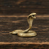 A detailed brass snake sculpture with an Art Deco design resting on a dark wooden surface.