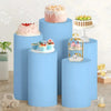 A display of pink and white tiered cakes and decorative items on light blue cylindrical stands for party decor