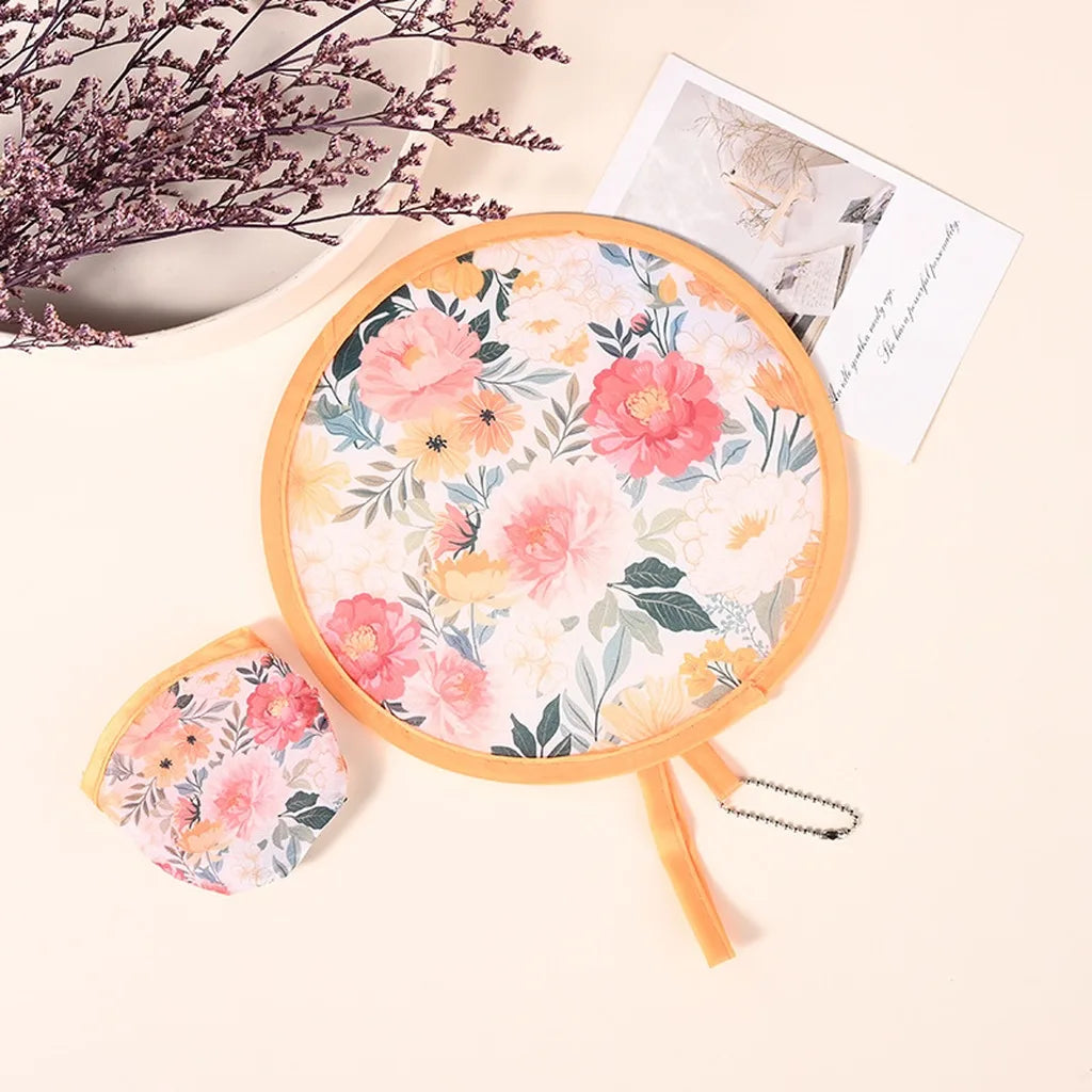 A pink floral patterned portable foldable cooling handheld fan with a wooden handle and a matching card.
