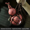 A traditional ceramic wine gourd with a narrow neck is suspended by twine, showing its size and texture.