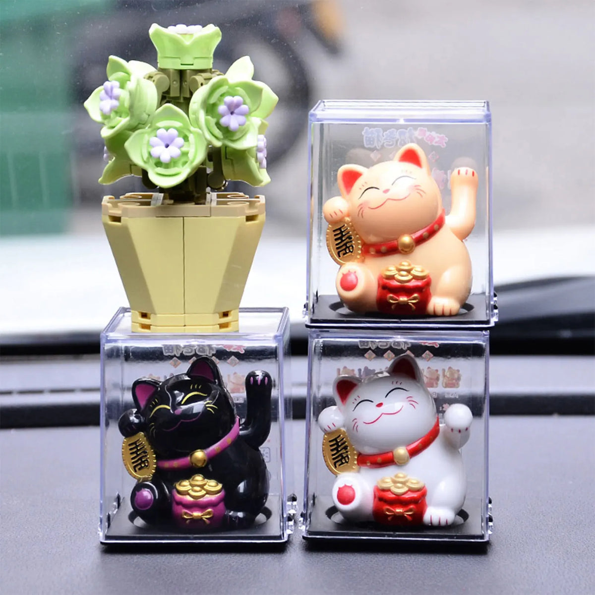 A set of solar-powered waving lucky cat figurines in various colors and sizes displayed on a dark surface.