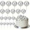 A collection of twenty silver foam ball cake toppers on white sticks arranged for party decorations.